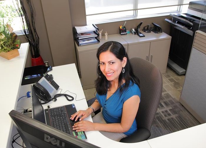 office administration professional typing at computer smiling. 