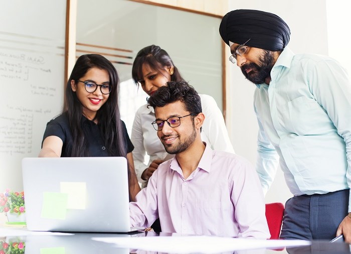 business people smiling around laptop