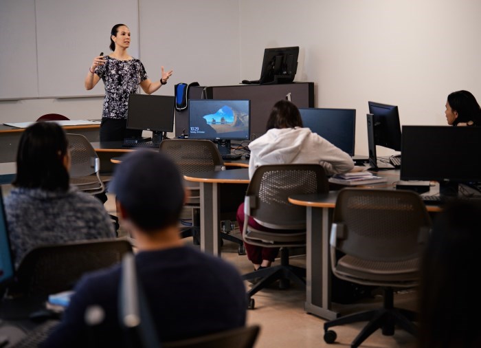 teacher in front of a computer lab teaching students 