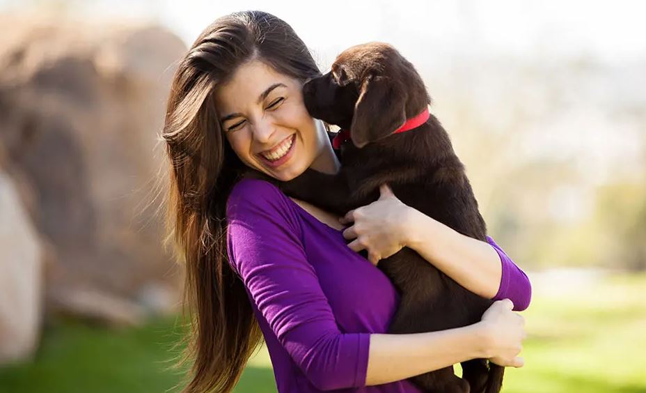 woman holding puppy smiling 