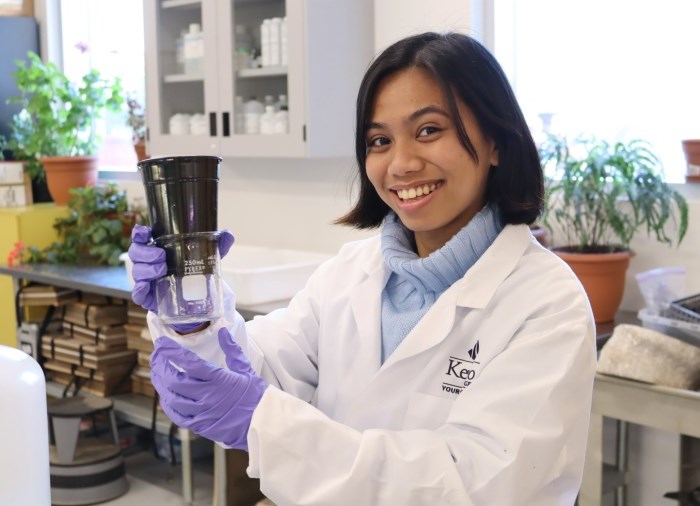 student in classroom with beaker