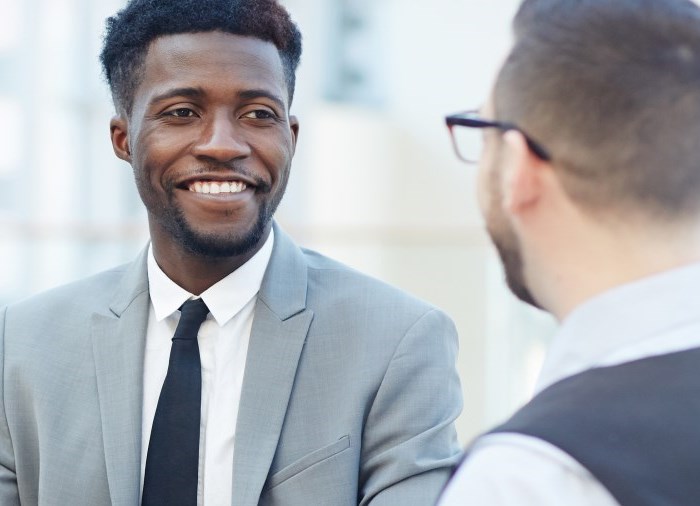 business man in suit talking and smiling with another man in suit