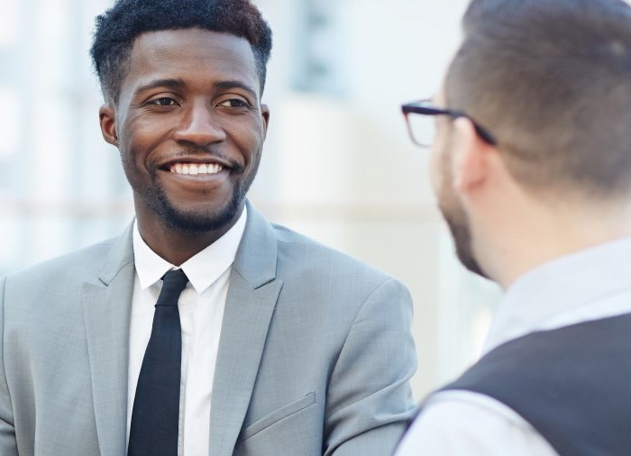 business men in suits smiling talking to each other