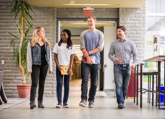 four students walking down hallway towards camera