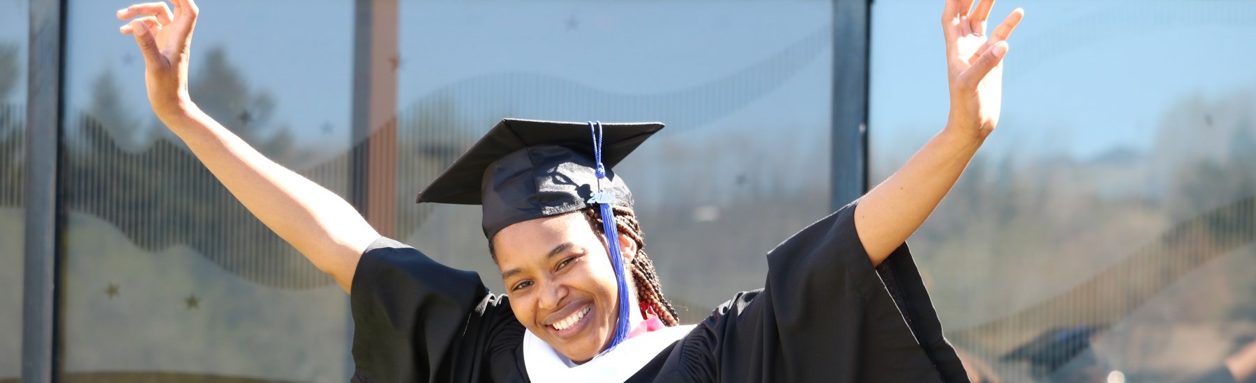 students wearing graduation cap and gown smiling 