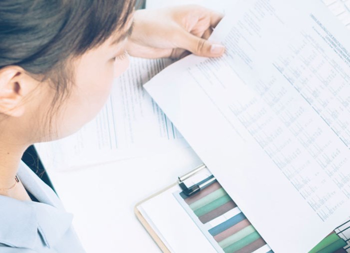 woman holding a form in front of a computer