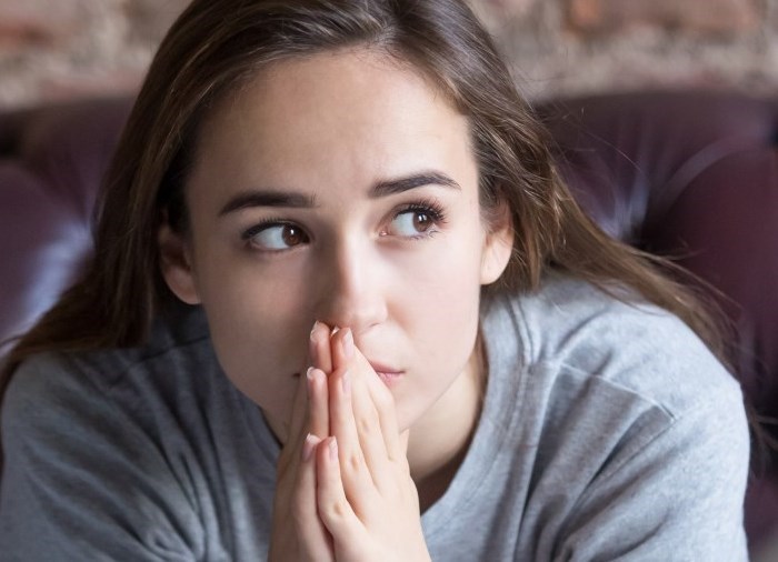 Woman clasping her hands, speaking to counsellor.