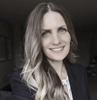 smiling woman with long blonde hair wearing a dark business suit