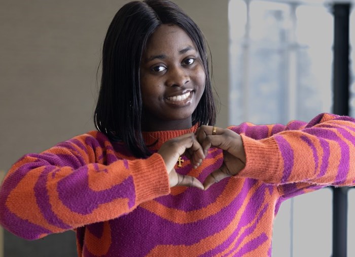 Student Cynthia smiling with her hands shaped in a heart formation.