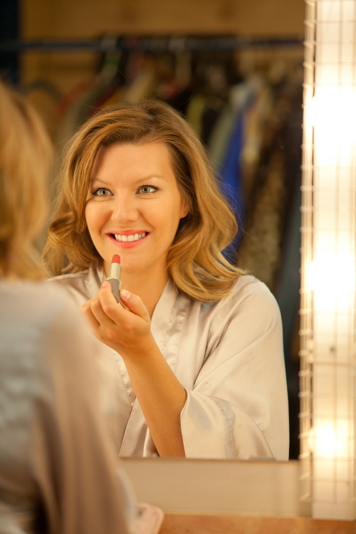 Actress looking in dressing room mirror applying stage makeup