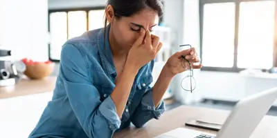 Stressed business woman working from home on laptop looking worried, tired and overwhelmed.