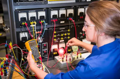 Person in a lab using a digital multimeter to test electrical circuits on a control panel with multiple wires, gauges, and switches.