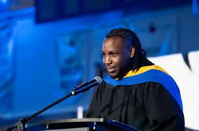 A graduate in academic regalia speaks at a podium during a convocation ceremony.