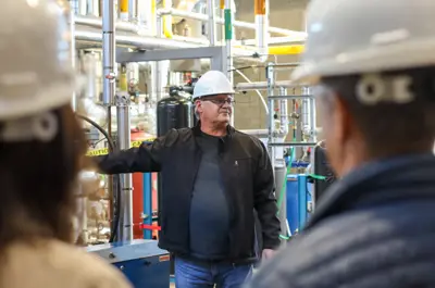 A guy wearing a white safety hat standing in a power engineering lab