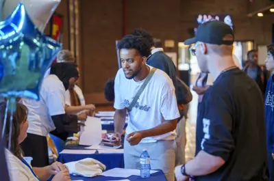 A guy is bending down talking to a staff who is sitting