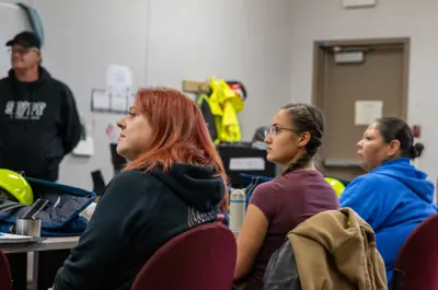 Three women and a man paying attention to someone talking