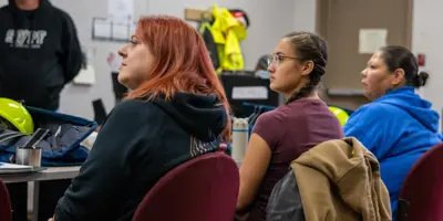 Three women and a man paying attention to someone talking