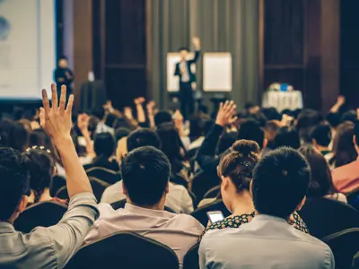 Speaker on the stage with Rear view of Audience in the conference hall or seminar meeting, business and education concept