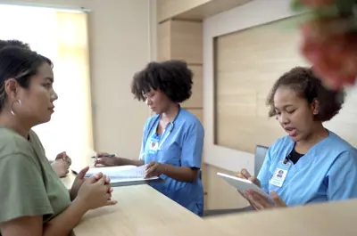 People making an appointment with medical staffs at reception desk in hospital. Medical staff and nurse - receptionist talking to patient in front of the reception counter in hospital.
